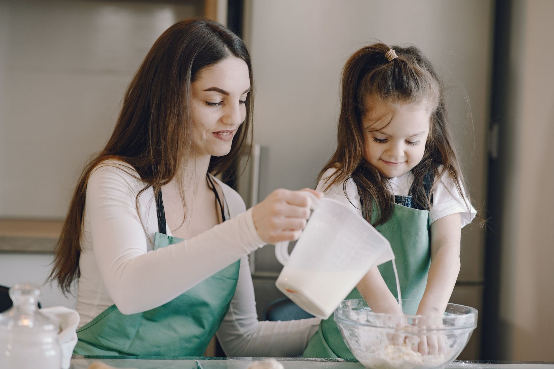 A loving mother and daughter sharing a joyful moment while baking in the kitchen together.