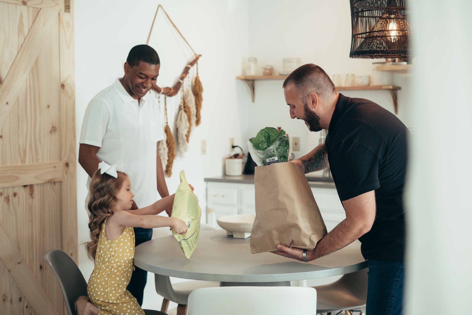 A cheerful family unpacks groceries in a bright kitchen, sharing a joyful moment together.